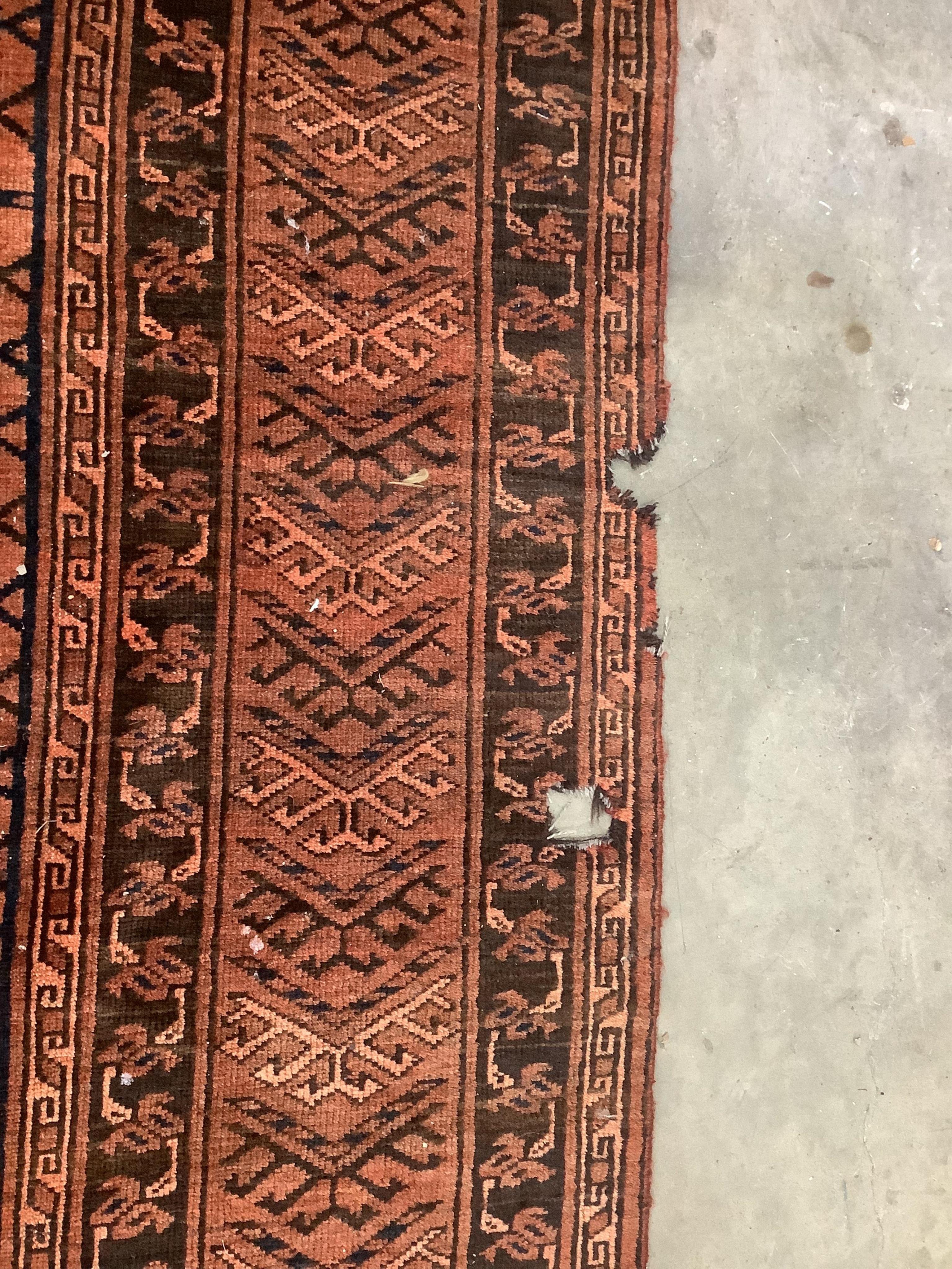 An Afghan rust ground carpet, 400 x 260cm. Condition - poor, damage to border